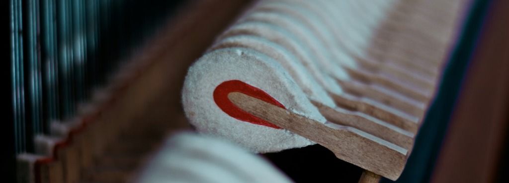 Vista interna de la maquinaria de un piano abierto para mantenimiento, mostrando las piezas complejas