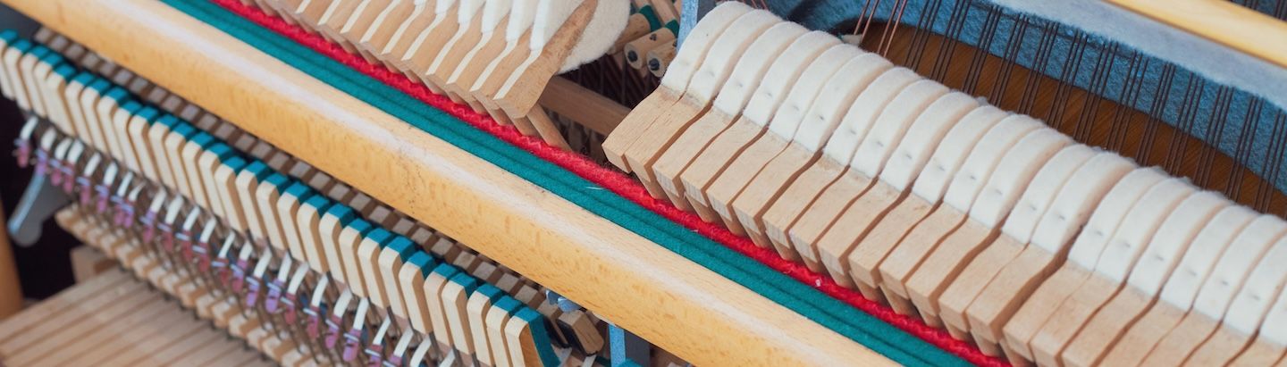 Muestrario de pianos restaurados y detalles técnicos del proceso de reparación en el taller